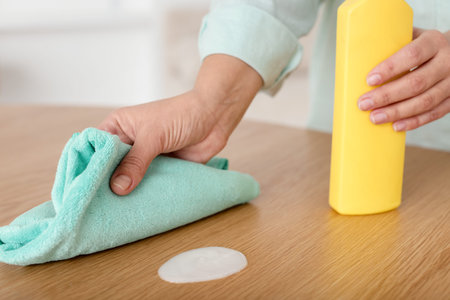 Woman polishing wooden table at home, closeup