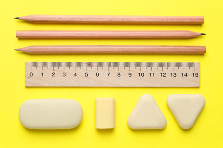Erasers and other stationery on yellow background, flat layの写真素材