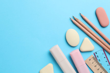 Erasers and other stationery on light blue background, flat lay. Space for textの写真素材