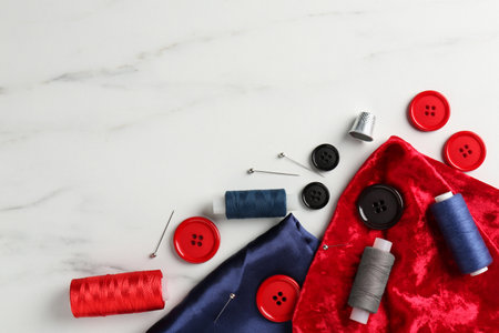 Different sewing supplies on white marble table, flat lay. Space for textの写真素材
