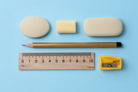 Erasers and other stationery on light blue background, flat layの写真素材