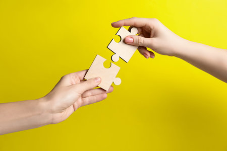 Business strategy and teamwork concept. Partners putting puzzle pieces together on yellow...
