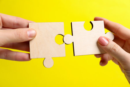 Business strategy and teamwork concept. Partners putting puzzle pieces together on yellow background, closeupの写真素材