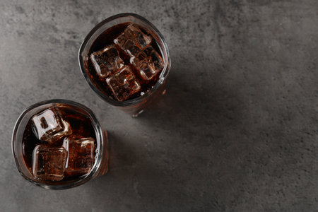 Cold cola with ice cubes in glasses on gray table, top view. Space for textの写真素材