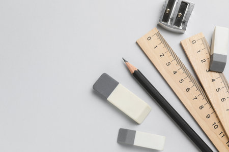 Erasers, pencil, sharpener and rulers on light background, top view. Space for textの写真素材
