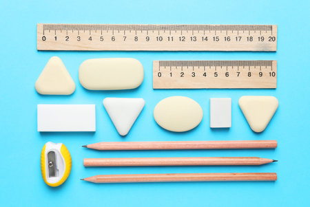 Erasers and other stationery on light blue background, flat layの写真素材
