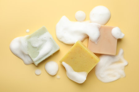 Soap bars with foam on yellow background, flat layの写真素材