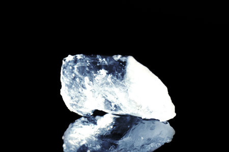 Piece of clear ice on black mirror surfaceの写真素材