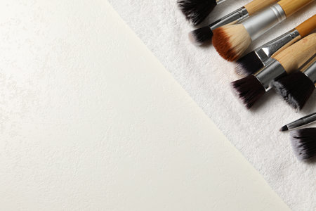 Clean makeup brushes with towel on white table, top view. Space for textの写真素材
