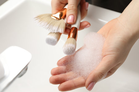 Woman washing makeup brushes with soap over sink, closeupの写真素材