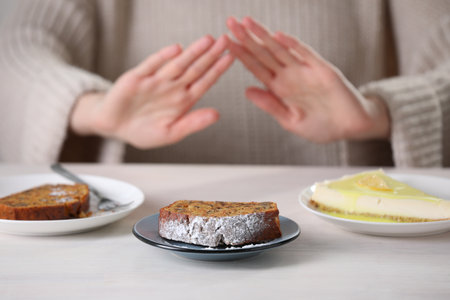 Woman refusing to eat products at table indoors, selective focus. Food allergy conceptの写真素材