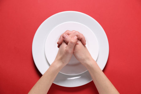 Woman holding hands together over plates on red background, top viewの写真素材