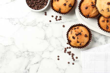 Delicious muffin with chocolate chips on white marble table, flat lay. Space for textの写真素材