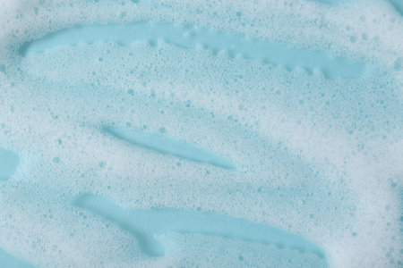 White fluffy foam on light blue background, top viewの写真素材