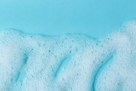 White fluffy foam on light blue background, top view. Space for textの写真素材