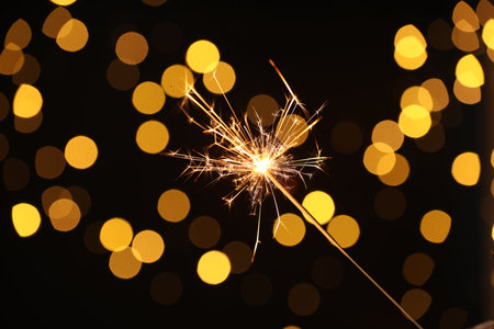 Bright burning sparkler on dark background with blurred lights, bokeh effectの写真素材