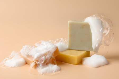 Soap bars with foam on beige background, closeup. Space for textの写真素材