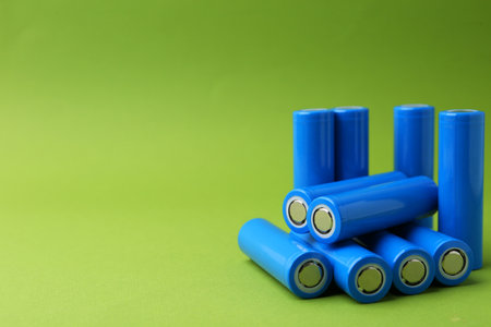Many AA cell batteries on green background, closeup.の写真素材