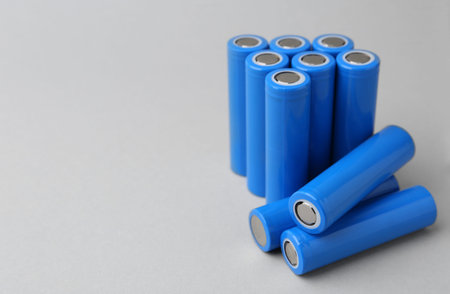 Many cell batteries on light gray background, closeup. Space for text