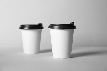 Paper cups with lids on grey background. Mockup for designの写真素材