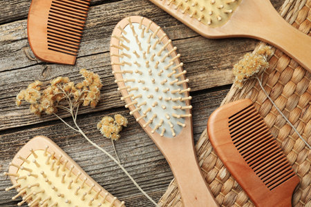 Hair brushes, combs and dried flowers on wooden background, flat layの写真素材
