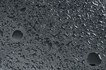 Water drops on dark grey glass surface, closeup