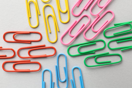 Colorful paper clips on light background, flat lay