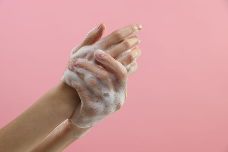 Woman washing hands with foaming soap on pink background, closeup with space for text. Hygieneの写真素材
