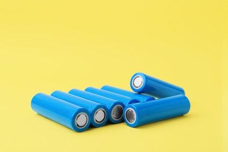 Many AA cell batteries on yellow background. Space for textの写真素材