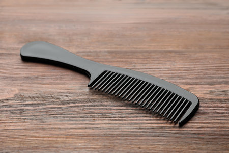 One black plastic comb on wooden table, closeupの写真素材