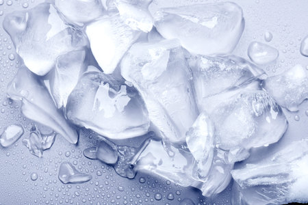 Pieces of crushed ice on light background, top view