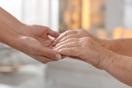 Caregiver supporting senior woman on light background, closeup. Elderly careの写真素材