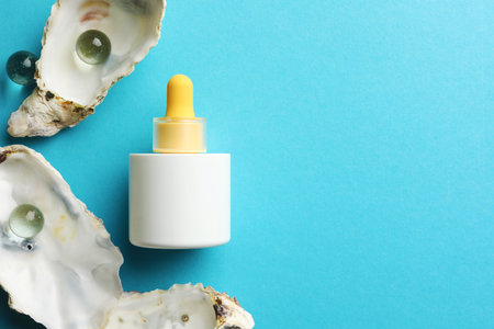 Bottle of skin care product, seashells and glass balls on light blue background, flat lay. Space for textの写真素材