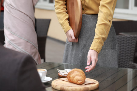 Waitress taking tips from wooden table in outdoor cafe, closeup