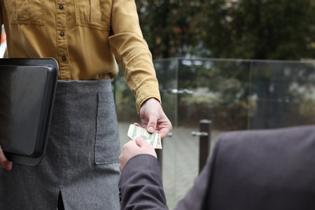 Client giving tips to waitress in outdoor cafe, closeupの写真素材