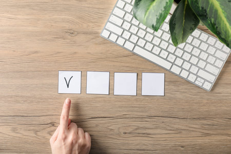 Person pointing at checkbox with tick mark at wooden table, top viewの写真素材