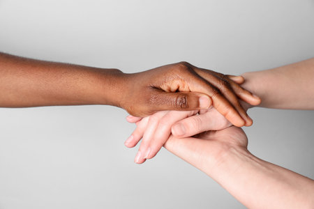 Stop racism. People of different skin colors holding hands on light grey background, closeupの写真素材