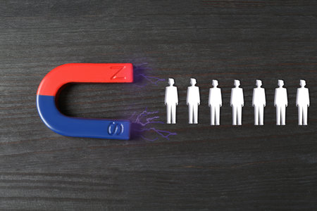 Magnet attracting white figures on wooden background, top view.の写真素材