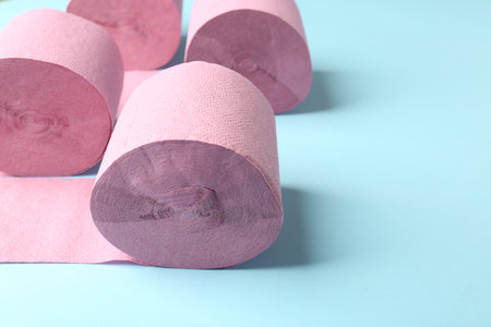 Pink toilet paper rolls on light blue background, closeup. Space for textの写真素材