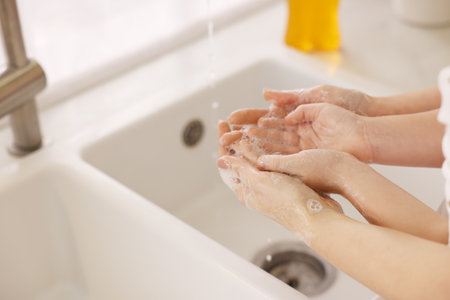 Mother and daughter washing their hands indoors, closeup. Space for textの写真素材