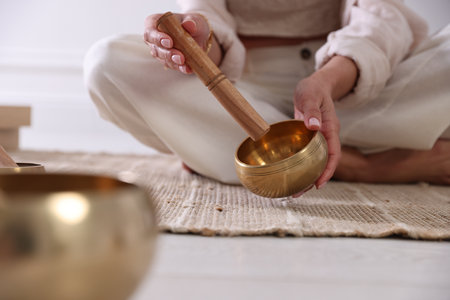 Woman with singing bowls on floor indoors, closeupの写真素材