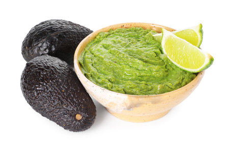 Tasty avocado dip in bowl and lime isolated on whiteの写真素材