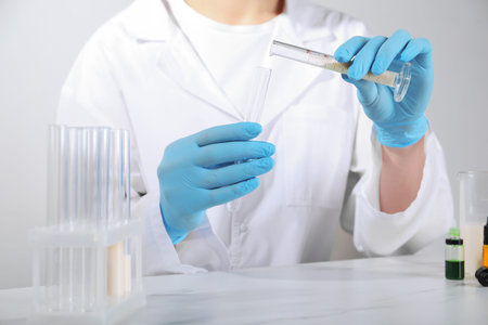 Laboratory testing. Scientist working with test tubes at white marble table, closeup