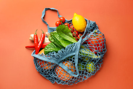 Net bag with products on orange background, top view. Eco friendly lifestyleの写真素材