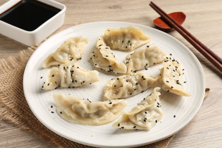 Delicious gyoza dumplings with sesame seeds served on wooden table, closeupの写真素材