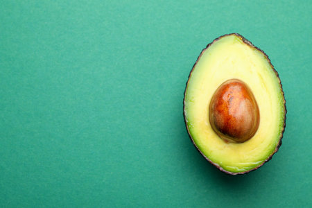 One cut ripe avocado on teal background, top view. Space for textの写真素材