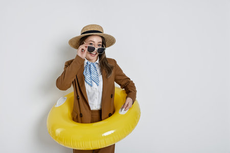 Businesswoman with inflatable ring, straw hat and sunglasses on white background, space for textの写真素材