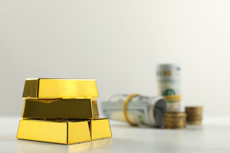 Shiny gold bars and money on light background, selective focus. Space for textの写真素材