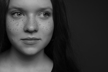 Beautiful teenage girl with freckles on dark background, closeup. Black and white effectの写真素材
