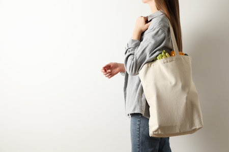 Woman holding shopper bag with groceries on white background, closeup and space for text. Eco friendly lifestyleの写真素材